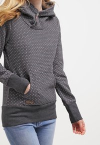 Sudadera de color gris carbón con patrón de lunares, cuello de embudo con botones, bolsillo frontal y puños y dobladillo de canalé. Textura suave.