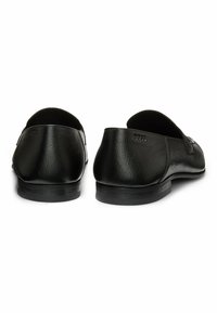 Svarta läderslip-ons med en slät yta, rund form och minimalistisk design. Logotyp präglad på baksidan, platt gummisula.