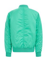 Vihreä pommikapakka, joka on valmistettu kiiltävästä ja sileästä kankaasta. Ominaisuuksiin kuuluu ribbireunukset, näkyvät saumat ja sivutasku.