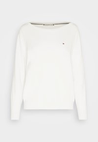 Pull blanc à manches longues en matière douce, avec un col bateau et un petit logo sur la poitrine. Texture lisse.