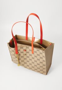 Borsa tote beige con motivo logo nero, manici in pelle arancione e interno dorato. Presenta un compartimento con zip e un charm.