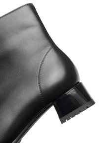 Zwarte leren enkelboot met een gladde textuur, ronde neus en een chunky hak met een glanzend zwart accent en een loopvlak met profiel.