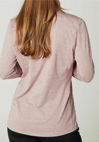 Lyserød langærmet top med tekstureret stof og en afslappet pasform. Har diskrete mønstre og en krave, kombineret med sorte bukser.