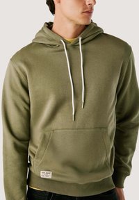 Olijfgroene hoodie van zachte stof, met een voorste buidelzak, verstelbare koorden met metalen uiteinden en een geribde zoom.