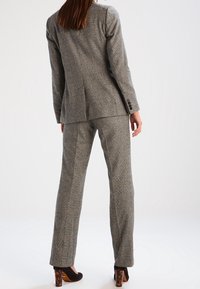 Grå rutiga kavaj och matchande byxor, texturerad väv, figursydd design, enkel knäppning, avslutad med ett subtilt rutig mönster.