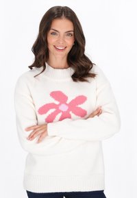 Sweter w kolorze off-white z okrągłym dekoltem i długimi rękawami. Posiada duży różowy wzór kwiatu na środku oraz ściągacze na rękawach i u dołu.