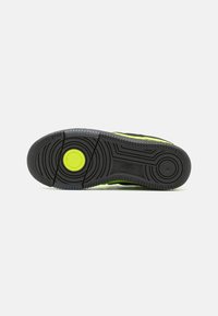 Black and yellow Nike sneaker sole with textured rubber, circular tread pattern, and a prominent logo detail near the center.