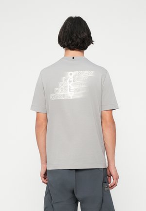T-shirt in cotone grigio con stampa grafica bianca sulla schiena. Maniche corte e design a girocollo. Texture liscia.