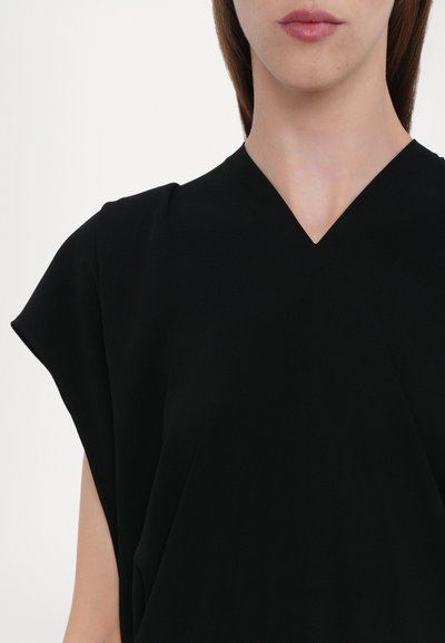 Black v-neck top with short, structured sleeves made of a smooth fabric. Features a relaxed fit and clean lines without visible fasteners.