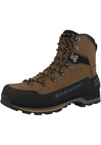 Bottes de randonnée marron avec capuchon en caoutchouc noir, accents gris et jaune, œillets en métal et tige texturée pour plus de durabilité et de soutien.