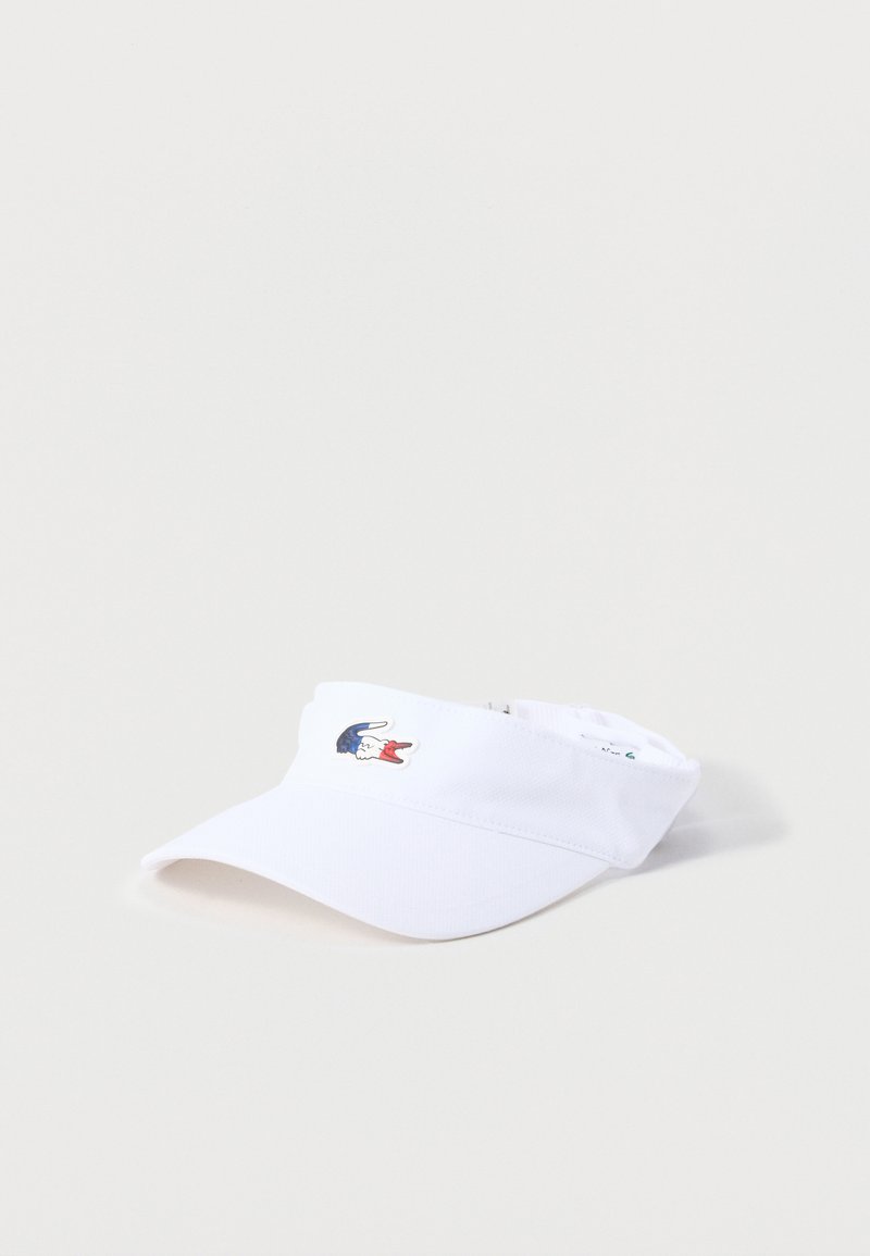 Άσπρο αθλητικό καπέλο με προσαρμοζόμενο πίσω λουρί και μικρό κεντημένο λογότυπο ενός μπλε, λευκού και κόκκινου κροκόδειλου στο μπροστινό μέρος.