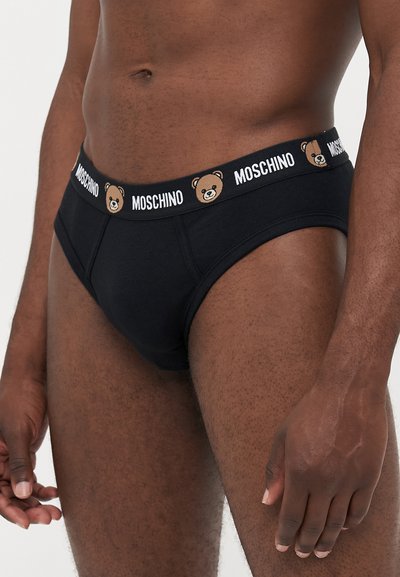 Boxeri din bumbac negru, cu un brâu cu model care prezintă grafica ursului și logo-ul "Moschino" în alb. Construiți cu un croi strâmt.
