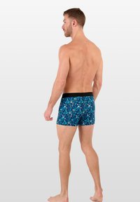 Boxers bleus à motifs avec une taille noire, présentant un design de style cartoon de diverses formes et couleurs, fabriqués en tissu doux.