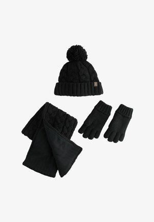Conjunto de invierno negro de punto con gorro de pom-pón, bufanda de punto trenzado forrada de forro polar y guantes de puño acanalado sobre un fondo blanco.