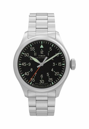 Timex Waterbury käekell roostevabast terasest käevõru, musta sihverplaadi, helendavate osutite ja punase sekundi osutiga, kell näitab aega 10:08:35.