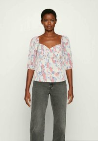 Top leve com padrão floral, decote quadrado, mangas curtas em balão e um ajuste estruturado. Apresenta cores em rosa, azul e branco.