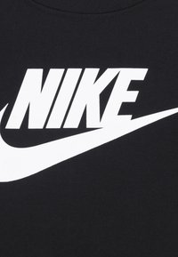 Fekete pamut póló, amelyen egy feltűnő fehér "NIKE" logó és jellegzetes swoosh minta látható, sima textúrával és klasszikus, kerek nyakkivágással.