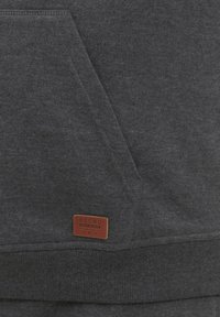 Sudadera gris oscuro con un bolsillo frontal, puños de canalé y una etiqueta de tela que dice "BLEND". Textura suave y diseño casual.