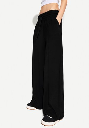 Black wide-leg sweatpants with an elastic waistband, drawstring closure, and side pockets, made from a soft fabric for comfort.
