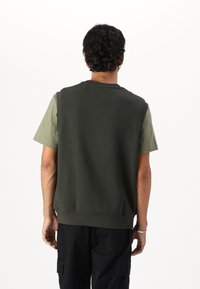 Felpa senza maniche verde oliva con scollo rotondo e maniche corte verde neutro, caratterizzata da una texture morbida e una vestibilità rilassata.