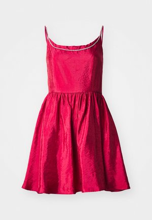 Piros ruha spagetti pántokkal, testhezálló felsőrésszel és bővülő szoknyával. Texturált anyag fényes felülettel és díszített dekoltázzsal.