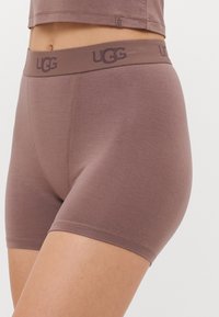 Smeđi UGG bokserice izrađene od mekog materijala, sa elastičnim pojasom s logotipom, bešavnom dizajnom i udobnim krojem.