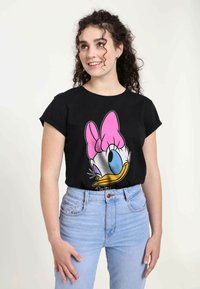 Sort t-shirt med korte ærmer, der præsenterer en farverig grafik af en tegneserieand med en lyserød sløjfe, parret med lysblå højtaljede jeans.