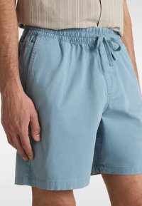 Lyseblå badebukser lavet af letvægtsstof med elastisk talje og snøre. Har sidelommer og et afslappet pasformdesign.