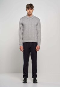 Polo grigio a maniche lunghe con texture a costine e colletto a tre bottoni, abbinato a pantaloni blu navy e scarpe nere stringate.