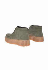 Stivali alla caviglia in pelle verde con superficie testurizzata e una suola spessa e scanalata di colore beige. Presentano cerniere laterali per una facile vestibilità.