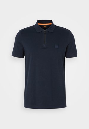Navy polo shirt with a zippered collar, featuring a small logo patch on the chest and short sleeves. Cotton blend material with a smooth texture.