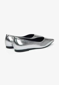 Srebrne metaliczne baleriny z wąskim noskiem i niską czarną podeszwą. Gładka powierzchnia z eleganckim, odbijającym światło wykończeniem. Otwarta konstrukcja po bokach zapewniająca wentylację.