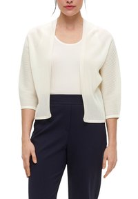 Open-front cardigan in zacht beige met ribbeltextuur, 3/4 mouwen en een ontspannen pasvorm. In combinatie met een licht tanktop en donkere broek.