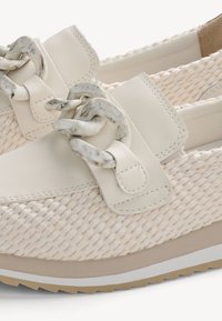 Zapatos beige de tejido trenzado tipo slip-on con detalle de cadena marmolada gruesa y suela acolchada diseñados para uso casual y confort.