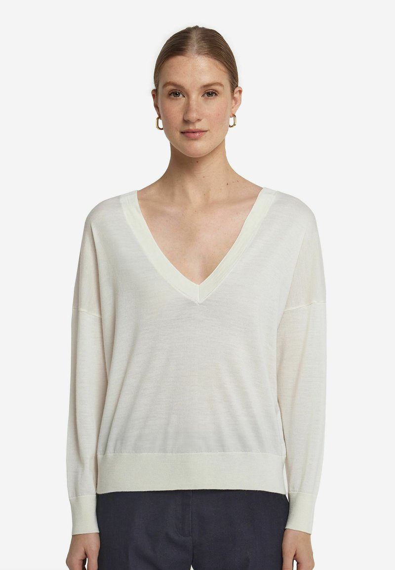 Cremfarbener V-Ausschnitt-Pullover mit langen Ärmeln und geripptem Saum. Leicht, mit weicher Textur, lockerer Passform und subtilen Nähten.