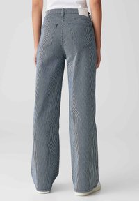 Pantalons larges rayés bleu et blanc avec taille haute, bande élastique et deux poches arrière, fabriqués dans un tissu léger.