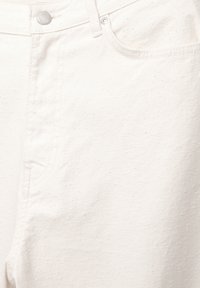 Vita denimjeans med en strukturerad yta, som har fickor, knäppning med knapp och ton-i-ton sömmar. Tyget har en lätt stretch.