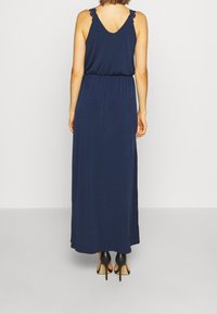 Granatowa maxi sukienka z okrągłym dekoltem i koronkowymi akcentami na ramiączkach. Elastyczna talia i lekka tkanina zapewniająca swobodny krój.