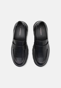 Zwarte leren loafers met een gladde afwerking, voorzien van een opvallende band en contrasterende stiksels langs de zool. Rond toel ontwerp.