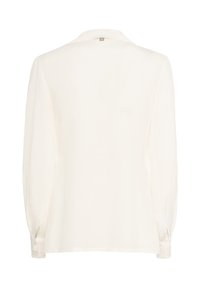 Blusa bianca a maniche lunghe con polsini bottonati e un piccolo’etichetta sulla parte posteriore del colletto, mostrata da dietro su uno sfondo bianco.