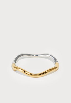 Hullámos dizájnnal készült fém karkötő, amely fényes ezüst és arany felével rendelkezik, sima textúrával és fényes felülettel.