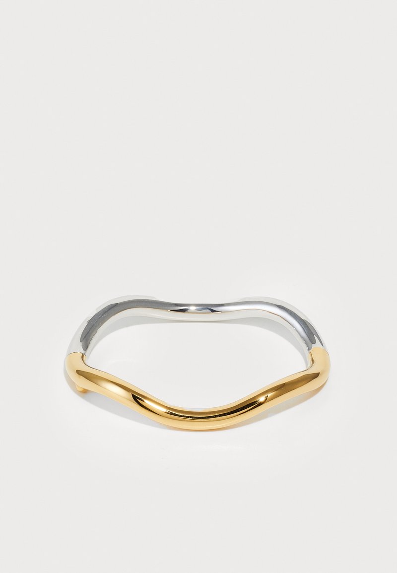 Hullámos dizájnnal készült fém karkötő, amely fényes ezüst és arany felével rendelkezik, sima textúrával és fényes felülettel.