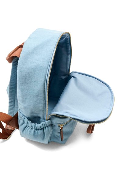 Jasnoniebieski plecak wykonany z tkaniny z złotym zamkiem błyskawicznym, brązowymi skórzanymi akcentami oraz elastyczną boczną kieszenią. Wnętrze wyściełane materiałem w kolorze zewnętrznym.