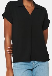 Blusa nera a maniche corte con colletto, caratterizzata da una scollatura a V e una vestibilità morbida. Realizzata in tessuto leggero con una texture liscia.