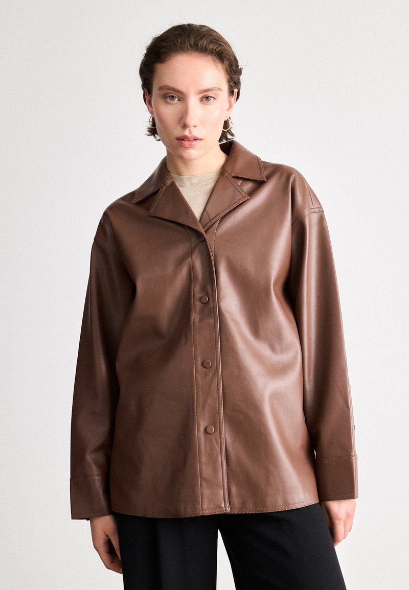 Camisa jaqueta de couro castanho com um design de gola, fecho frontal com botões e mangas longas. Textura suave com um ajuste descontraído.