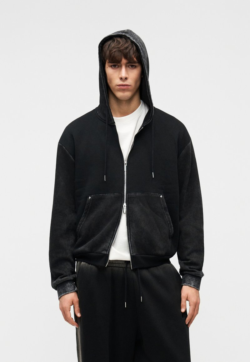 Μαύρο φούτερ με φερμουάρ και γκρι κουκούλα. Διαθέτει τσέπες μπροστά, ριμπ μανσέτες και άνετη εφαρμογή. Κατασκευασμένο από απαλό, υφαντό ύφασμα.