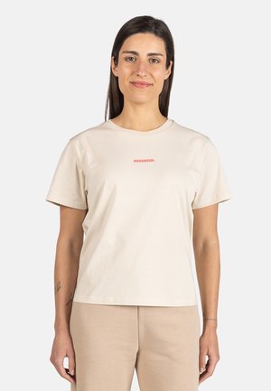 Beige bomulds t-shirt med rund halsudskæring, korte ærmer og et rødt logo centralt placeret på brystet. Glat tekstur med en afslappet pasform.