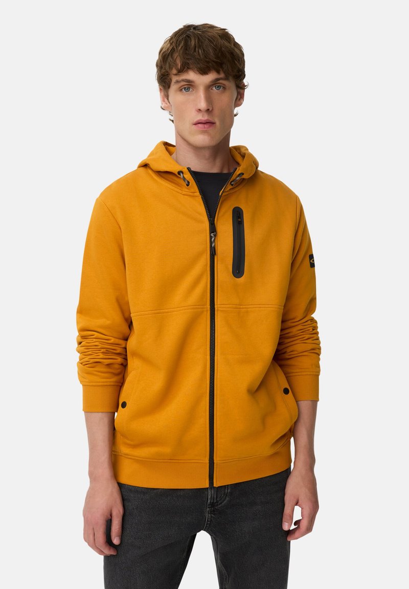 Haut à capuche jaune vif avec fermeture éclair, capuche réglable avec cordon, et poche zippée noire. Présente des poignets et un ourlet côtelés.