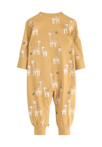 Jumpsuit jaune en tissu doux mettant en avant un motif répétitif de girafe en brun clair et blanc, avec des accents de feuilles vertes et des poignets élastiques.
