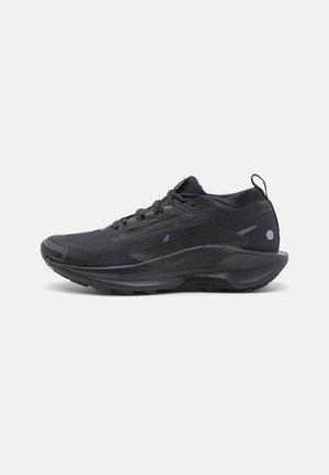 Schwarzer flacher Sportschuh mit strukturierter Sohle, Schnürdesign, Zuglasche an der Ferse und dezenten tonalen Mustern auf weißem Hintergrund.